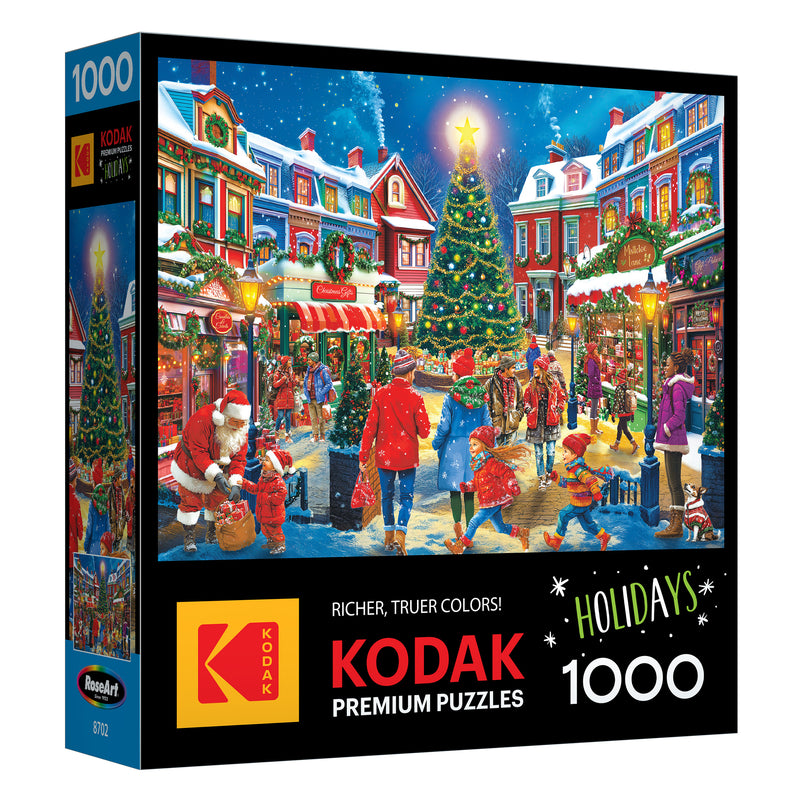 The image shows the ROSEART - KODAK PREMIUM Christmas Village 1000 piece jigsaw puzzle box with a festive holiday scene featuring a village, tree, people, and Santa Claus.