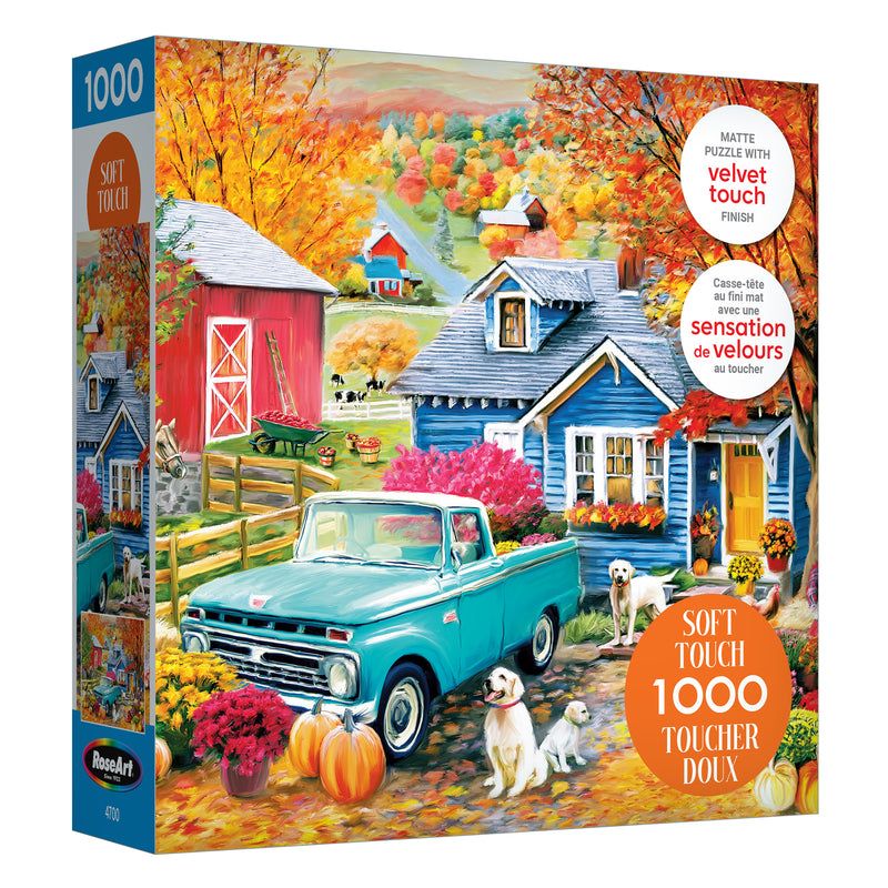 The ROSEART-SOFT TOUCH-AUTUMN HILL COTTAGE-1000 PIECE JIGSAW PUZZLE features a vibrant autumn farm scene with a blue pickup truck, dogs, pumpkins, barn, and house surrounded by colorful fall trees.