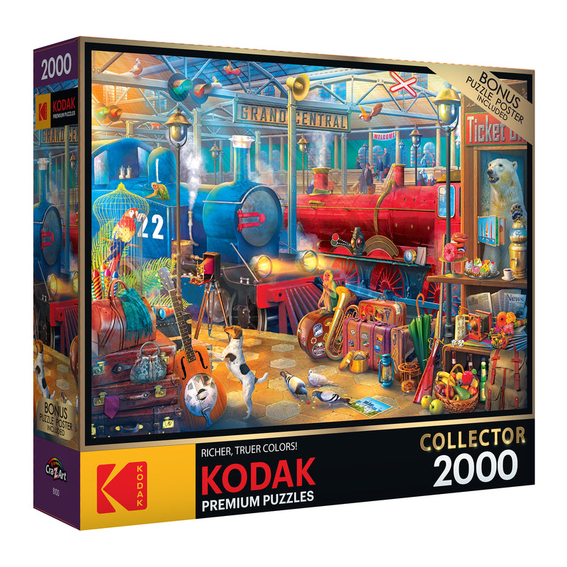 A RoseArt - Kodak Collector - Train Station - 2000 Piece Jigsaw Puzzle box featuring a colorful, detailed train station scene with diverse objects and characters. The box highlights "Richer, Truer Colors!" and includes a bonus poster.