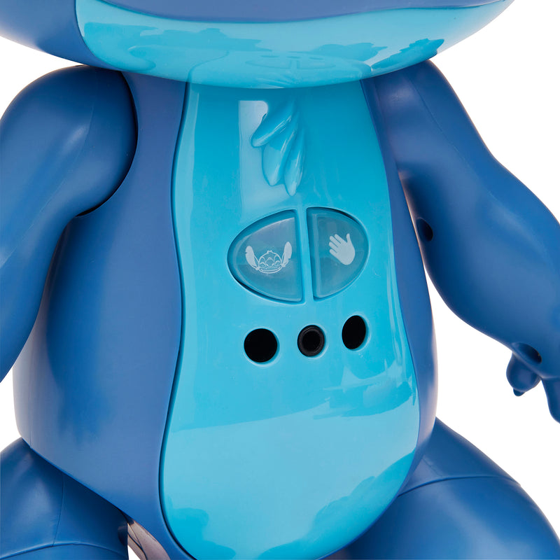 Close-up of a blue plastic toy with a smooth surface, two buttons featuring a cartoon face and a hand icon, and three circular speaker holes on its torso.