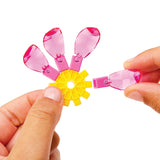 Hands delicately assembling a yellow gear with five pink translucent petal-like pieces, similar to the Crystal Gem Creations Blossoming Bonsai.
