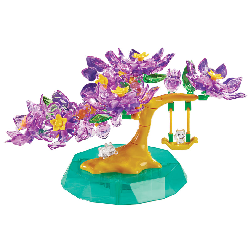 The Crystal Gem Creations Blossoming Bonsai features purple crystal-like leaves on a green base, complete with a swing holding a white cat and another cat sitting under the tree, adding charm to any space.