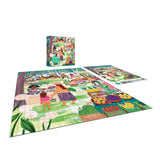A RoseArt-Soft Touch-Farmer's Market-1000 Piece Jigsaw Puzzle depicting a vibrant outdoor market scene with people shopping for fruits, vegetables, and goods. The completed puzzle lays next to its box and an image reference sheet.