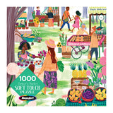 Illustration of a busy farmer's market with various stalls selling fresh produce, baked goods, and plants. Shoppers, including adults and children, browse and interact with vendors. RoseArt-Soft Touch-Farmer's Market-1000 Piece Jigsaw Puzzle.