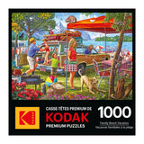 The image shows the box art of a RoseArt-Kodak Premium-Family Beach Vacation-1000 Piece Jigsaw Puzzle, depicting people setting up for a beach day with picnic tables, camping gear, and a lake in the background.