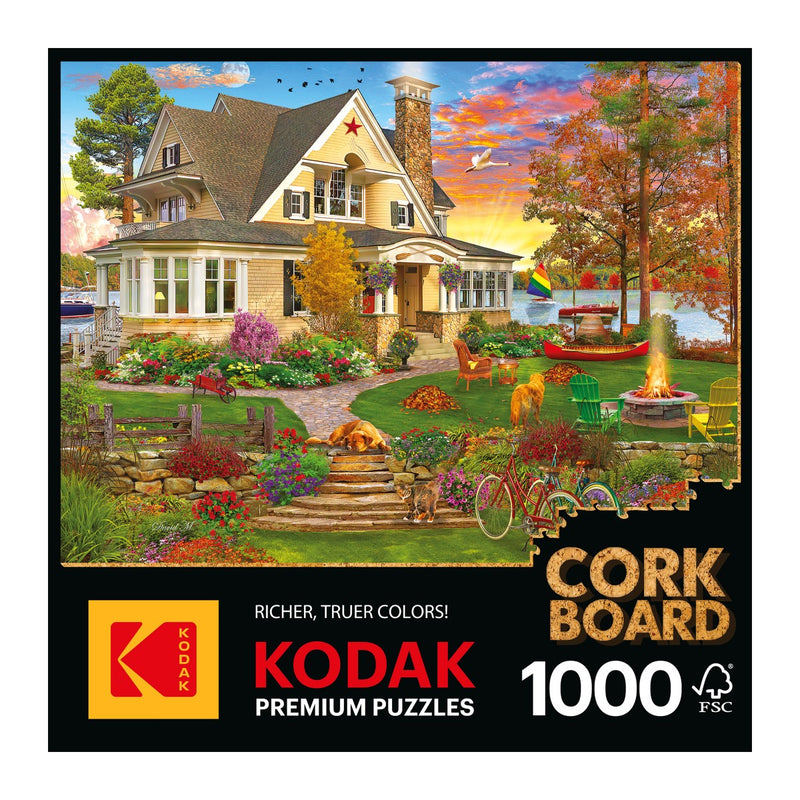 The box cover of the Cra-Z-Art - RoseArt - Kodak Cork - Lakeside Home 1000-piece jigsaw puzzle displays an autumn scene featuring a spacious lakeside home, surrounded by trees, a dog, and a garden. Entitled "Cork Board," this puzzle provides a serene retreat into scenic beauty.