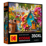 This jigsaw puzzle from the Songbirds 2 collection showcases a vibrant garden scene with a blue birdhouse, colorful flowers, and various cats lounging among pots. It features premium quality under the Kodak Premium Puzzles label and contains 350 extra-large pieces.