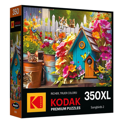 This jigsaw puzzle from the Songbirds 2 collection showcases a vibrant garden scene with a blue birdhouse, colorful flowers, and various cats lounging among pots. It features premium quality under the Kodak Premium Puzzles label and contains 350 extra-large pieces.
