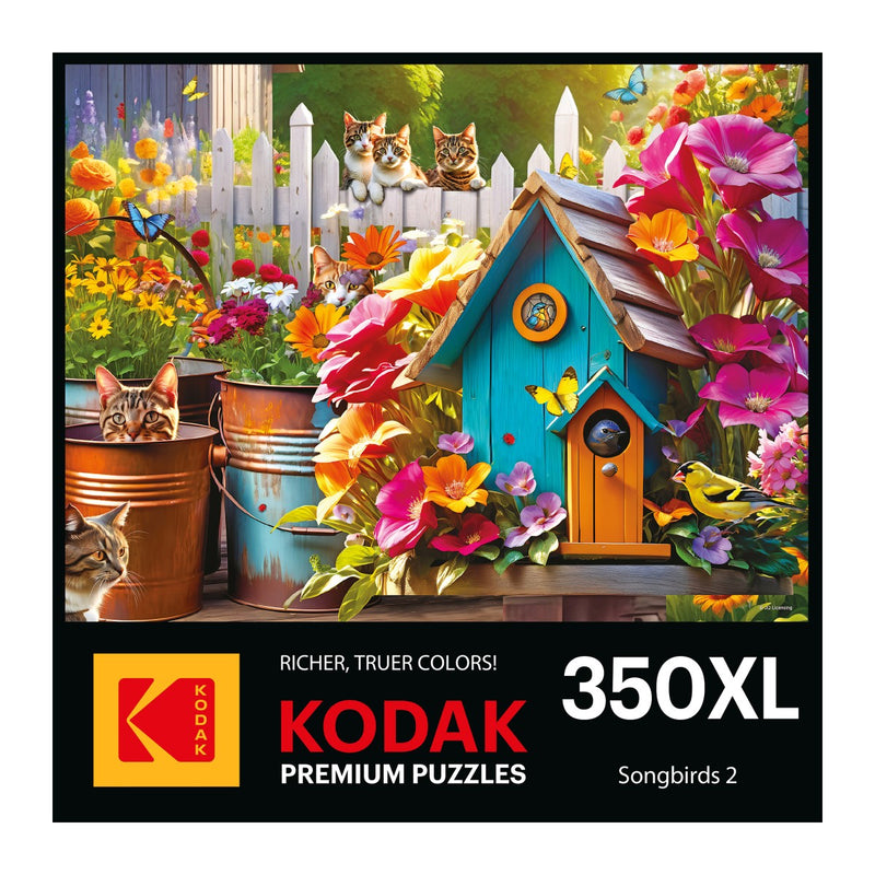 The puzzle box cover showcases vibrant flowers, a blue birdhouse with butterflies fluttering around, and three playful cats peeking over a white picket fence. The label reads "RoseArt - Kodak Premium - Songbirds 2 - 350 piece jigsaw puzzle.