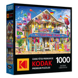 The ROSEART KODAK PREMIUM 1000-piece jigsaw puzzle box features a vibrant surf shack scene with surfboards, kites, and flags—ideal for enthusiasts.