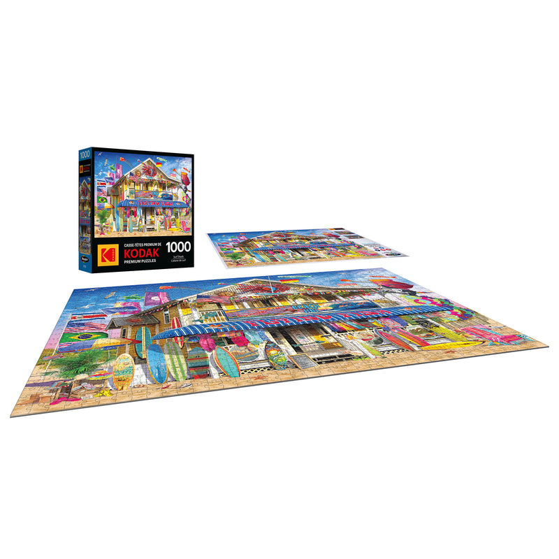 The completed ROSEART - KODAK Premium Surf Shack 1000-piece jigsaw puzzle is displayed next to its box, showing off vibrant surfboards.