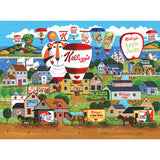 Illustration of a village scene with colorful hot air balloons featuring various Kellogg's cereal brands and vintage-style homes and buildings. Hot air balloons display cereal logos like Frosted Flakes and Apple Jacks, part of the RoseArt - Kellogg's - Hot Air Balloon Celebration - 1000 Piece Jigsaw Puzzle.