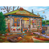 A colorful bait and tackle shop by the water offers boat rentals, live bait, and fishing gear. The scene includes fishing rods, buoys, a canoe, and ducks flying overhead in the RoseArt - Chris Bigelow - Castaway Bait and Tackle - 1000 Piece Jigsaw Puzzle.