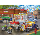 Colorful illustration of a vintage gas station with classic cars, a motorcycle, and a hot rod parked at the pumps. Buildings and colorful flags are in the background - RoseArt - Chris Bigelow - Hot Rod Garage - 1000 Piece Jigsaw Puzzle.