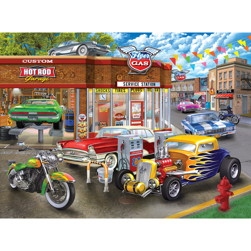 Colorful illustration of a vintage gas station with classic cars, a motorcycle, and a hot rod parked at the pumps. Buildings and colorful flags are in the background - RoseArt - Chris Bigelow - Hot Rod Garage - 1000 Piece Jigsaw Puzzle.