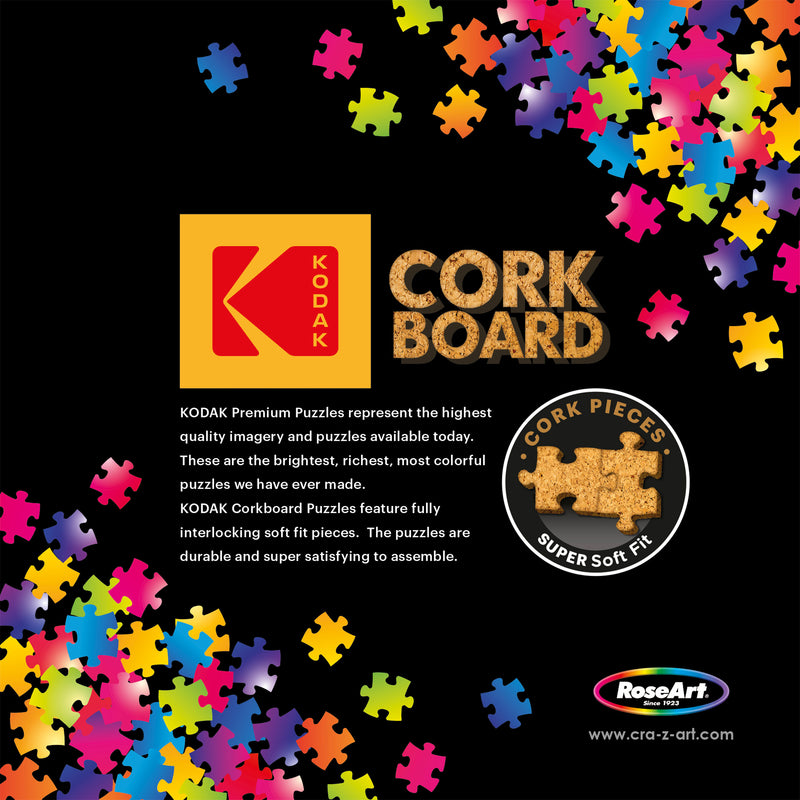 A RoseArt - Kodak Cork - Love is Everywhere - 1000 Piece Jigsaw Puzzle advertisement featuring colorful puzzle pieces on a black background. The text highlights the high quality of Kodak puzzles and the features of Corkboard puzzles by RoseArt.