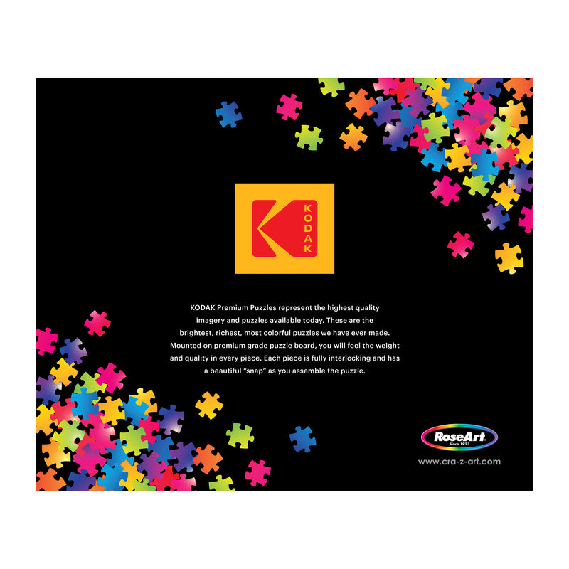 The ROSEART-KODAK Masters 'Two Sisters on the Terrace' 2000-piece jigsaw puzzle features a vivid black background with the Kodak logo encircled by colorful pieces, while the RoseArt logo completes the look below.