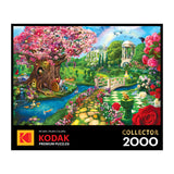Discover the ROSEART - KODAK PREMIUM SPRING GARDEN 2000-piece jigsaw puzzle, showcasing a vibrant fantasy garden with an enchanting pink blossom tree, a bridge, lush greenery, and a rainbow.