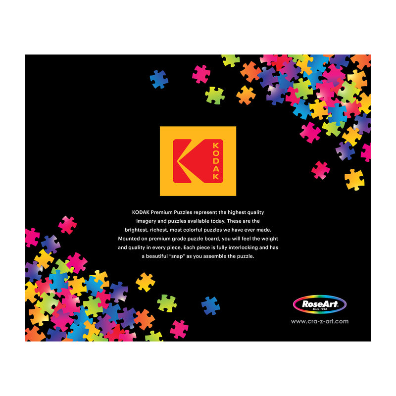 The black background features scattered colorful puzzle pieces alongside Kodak and RoseArt logos. Text highlights the vibrant imagery of the "ROSEART - KODAK PREMIUM - SPRING GARDEN - 2000 PIECE JIGSAW PUZZLE," emphasizing its high quality for enthusiasts.