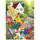 A woman with a basket picks flowers in a vibrant garden near a white house with a red roof—an idyllic scene captured in the ROSEART - SOFT TOUCH - PICKING FLOWERS - 1000 PIECE JIGSAW PUZZLE.