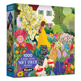 The ROSEART Soft Touch Picking Flowers 1000 Piece Jigsaw Puzzle features an illustration of a woman picking flowers in a vibrant garden before a white house.