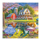 The ROSEART Soft Touch Backyard 1000 Piece Jigsaw Puzzle features a vibrant rural scene with a farmhouse, barn, horse, pond, picnic area, Adirondack chairs, and a dog on the colorful box.