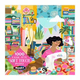 A woman sews a colorful quilt in a bright, fabric-filled room on the ROSEART Soft Touch Sewing Room 1000 Piece Jigsaw Puzzle.