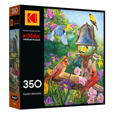 The ROSEART - KODAK PREMIUM "Garden Melodies" 350-piece jigsaw puzzle features colorful birds around a bell in a vibrant garden scene.