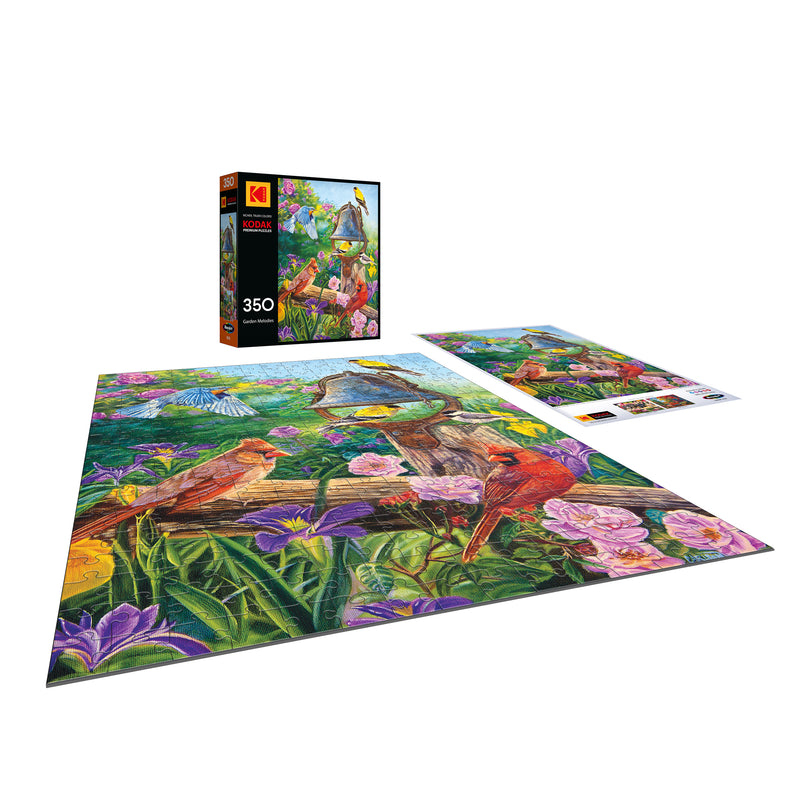 The ROSEART KODAK Premium Garden Melodies 350 piece jigsaw puzzle, featuring a vibrant bird and flower scene, is displayed completed beside its box and a reference image.