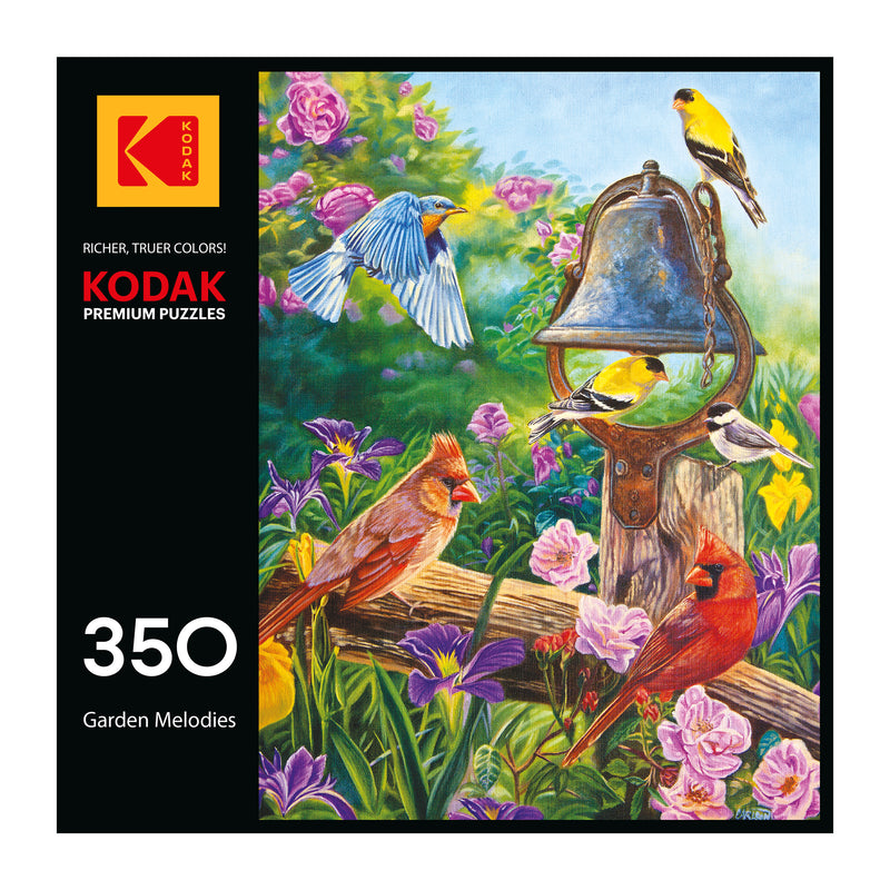 Box of a 350-piece ROSEART KODAK Premium "Garden Meolodies" jigsaw puzzle, featuring colorful birds by a metal bell in a lively flower garden.