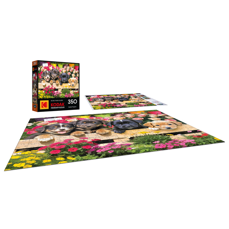 The ROSEART KODAK PREMIUM MARKET PUPPIES 350-piece jigsaw puzzle showcases adorable puppies at a vibrant market. The image displays both the finished puzzle and its box.