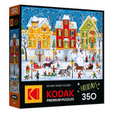 The ROSEART - KODAK PREMIUM "After the Snow Falls" 350-piece jigsaw puzzle features a festive winter village scene with snow, a horse-drawn sleigh, and people playing outside.