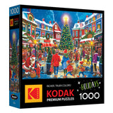 The image shows the ROSEART - KODAK PREMIUM Christmas Village 1000 piece jigsaw puzzle box with a festive holiday scene featuring a village, tree, people, and Santa Claus.