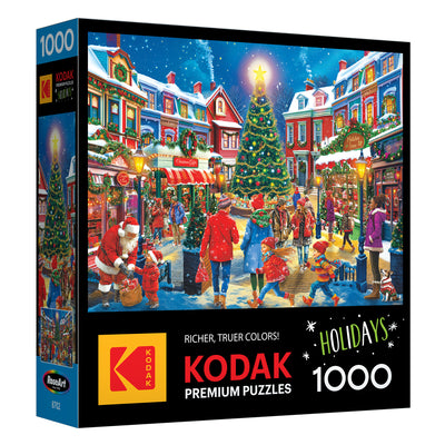 The image shows the ROSEART - KODAK PREMIUM Christmas Village 1000 piece jigsaw puzzle box with a festive holiday scene featuring a village, tree, people, and Santa Claus.
