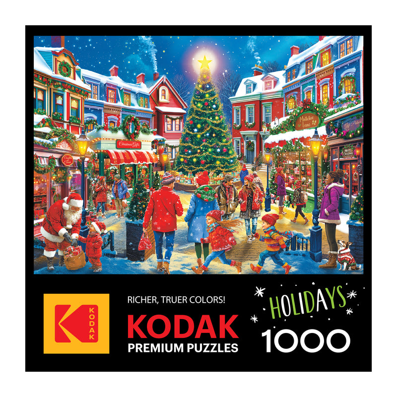 A festive holiday scene of people in winter clothes by a decorated Christmas tree in a charming village; ROSEART - KODAK PREMIUM - CHRISTMAS VILLAGE - 1000 PIECE JIGSAW PUZZLE.