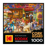 The ROSEART KODAK CORK "The Coffee Shop" 1000-piece jigsaw puzzle features a lively outdoor café scene with people, a dog, flowers, and a scooter.