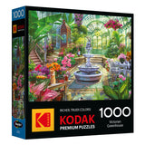 The ROSEART - KODAK PREMIUM - VICTORIAN GREENHOUSE 1000 piece jigsaw puzzle features artwork of a lush Victorian greenhouse with a central fountain and vibrant plants.