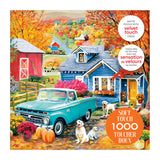 The ROSEART Soft Touch Autumn Hill Cottage 1000-piece jigsaw puzzle features a vibrant autumn farm scene with a blue vintage truck, two dogs, pumpkins, a red barn, and a blue house.