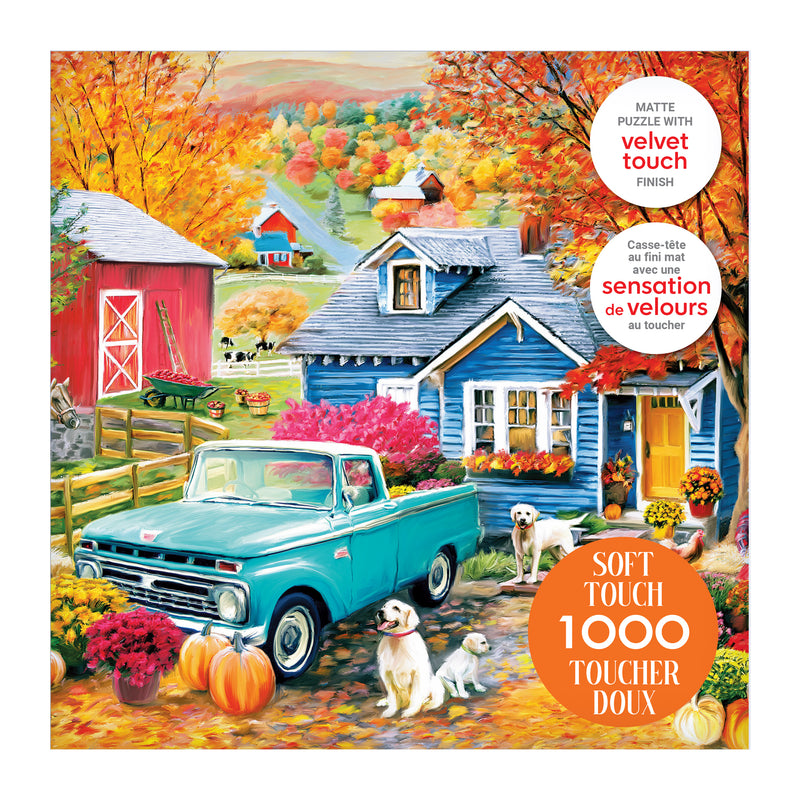 The ROSEART Soft Touch Autumn Hill Cottage 1000-piece jigsaw puzzle features a vibrant autumn farm scene with a blue vintage truck, two dogs, pumpkins, a red barn, and a blue house.