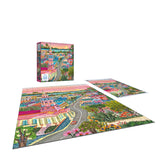 The ROSEART-MILLIE ILLUSTRATES-CHARLESTON-300 PIECE JIGSAW PUZZLE features colorful town artwork and is pictured completed, partially assembled, and next to its box.