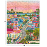 The ROSEART-MILLIE ILLUSTRATES-CHARLESTON 300-piece jigsaw puzzle features a vibrant illustrated town with a tall church, charming houses, gardens, and a scenic sunset waterfront. Size: 18x24 inches.