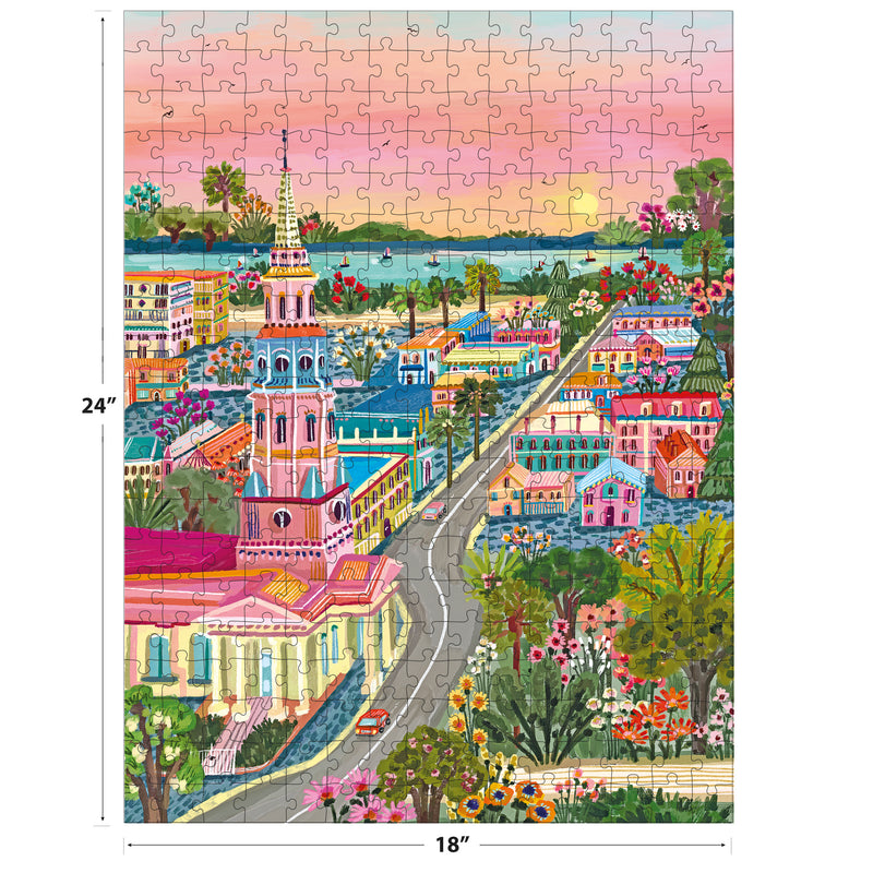 The ROSEART-MILLIE ILLUSTRATES-CHARLESTON 300-piece jigsaw puzzle features a vibrant illustrated town with a tall church, charming houses, gardens, and a scenic sunset waterfront. Size: 18x24 inches.