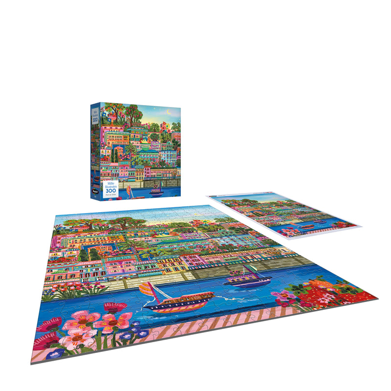 The ROSEART-MILLIE ILLUSTRATES-PORT DE SOLLER-300 PIECE JIGSAW PUZZLE features a colorful waterfront scene with boats, buildings, trees, and flowers. Shown completed alongside the puzzle box and an image sheet.