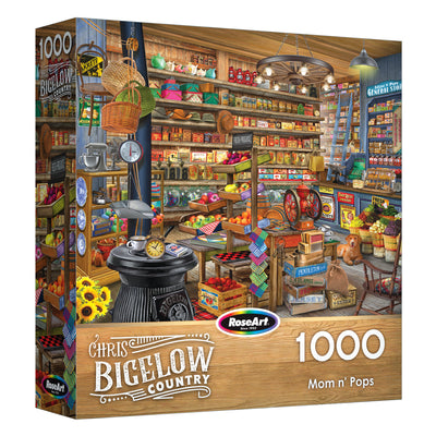 The ROSEART-BIGELOW COUNTRY-MOM AND POPS 1000 piece jigsaw puzzle box showcases a detailed vintage general store scene with shelves of goods and a wood-burning stove in the foreground.
