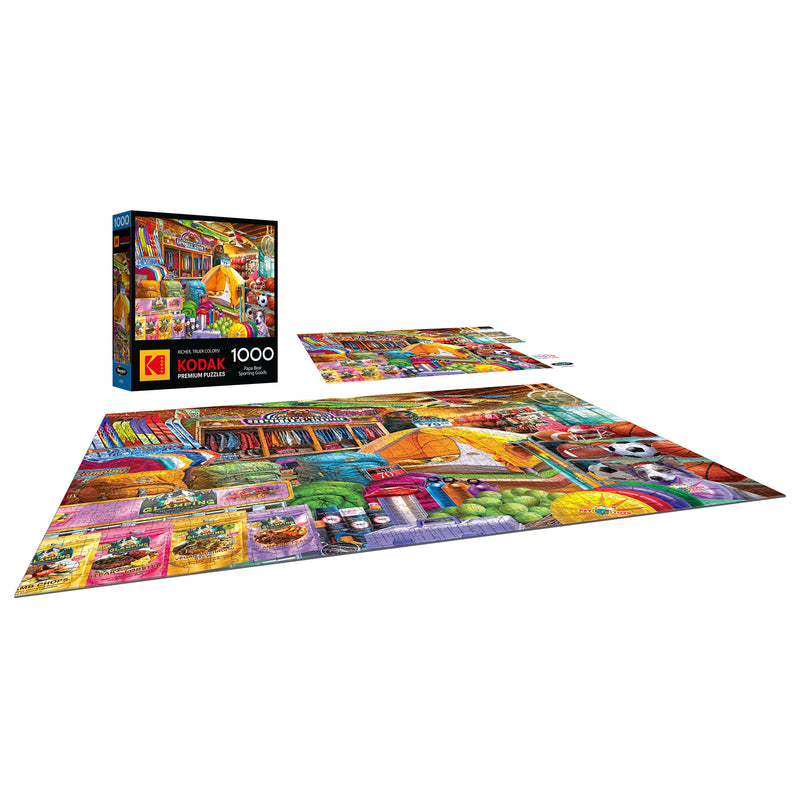 A completed ROSEART-KODAK PREMIUM "PAPA BEAR SPORTING GOODS" 1000-piece jigsaw puzzle is displayed, with the box and some partially assembled pieces visible nearby.