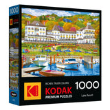 The ROSEART-KODAK PREMIUM-LAKE RESORT-1000 PIECE JIGSAW PUZZLE features a vibrant lake resort scene with boats, a dock, and people enjoying outdoor activities.