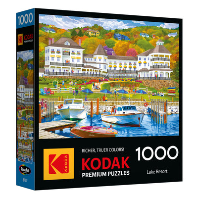 The ROSEART-KODAK PREMIUM-LAKE RESORT-1000 PIECE JIGSAW PUZZLE features a vibrant lake resort scene with boats, a dock, and people enjoying outdoor activities.