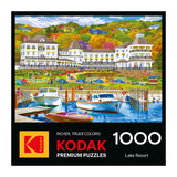 Illustration of a lively lake resort with people, boats, and a white hotel amid vibrant autumn trees; ROSEART-KODAK PREMIUM-LAKE RESORT 1000 piece jigsaw puzzle branding at the bottom.