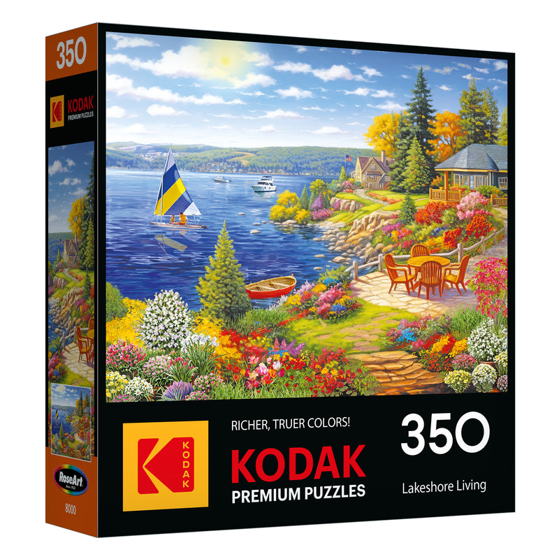 Enjoy the ROSEART-KODAK PREMIUM "Lakeshore Living" 350-piece jigsaw puzzle, featuring a scenic lakeside view with a sailboat, colorful flowers, trees, and a cozy patio.