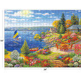 The ROSEART-KODAK PREMIUM-LAKESHORE LIVING 350 piece jigsaw puzzle (18x24 in) features a colorful lakeside garden, patio set, sailboats, charming houses and trees under a bright blue sky.